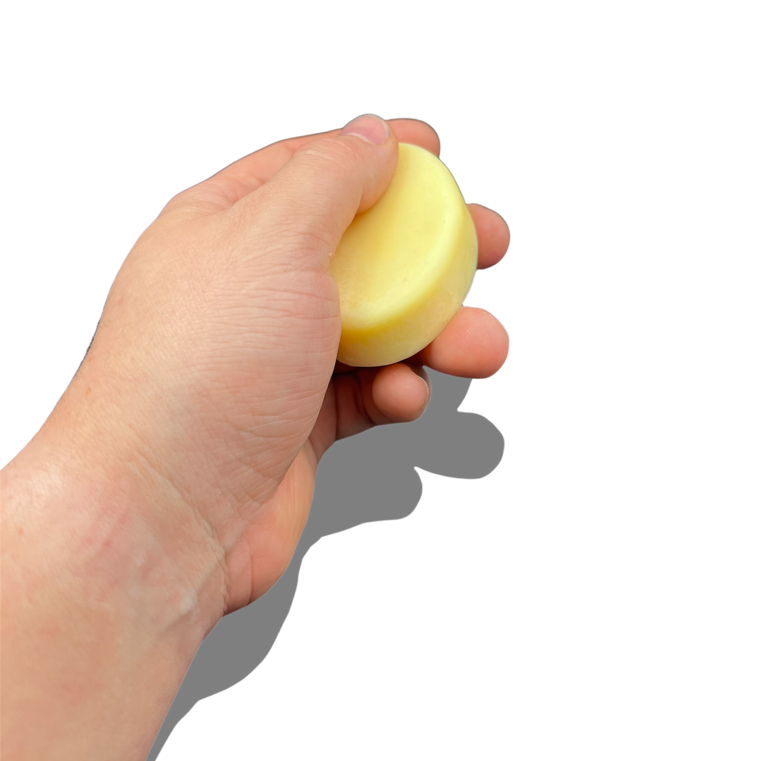 Ein Bild einer festen Handcreme in einer umweltfreundlichen Verpackung. Die Creme hat eine kompakte, solide Form und liegt neben frischen Pflanzen und Blüten, die die natürlichen Inhaltsstoffe symbolisieren. Die Szene ist hell und einladend, was die pflegende und nachhaltige Qualität der Handcreme unterstreicht.